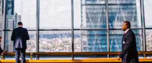 two men looking outside skyscraper