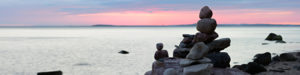 Balancing Stones on Sand Beach with Huge Boulders at Sunset