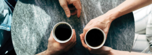 two people holding coffee mugs