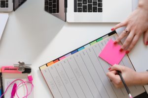 female' hand writing on post-it note - scheduling business mentor event