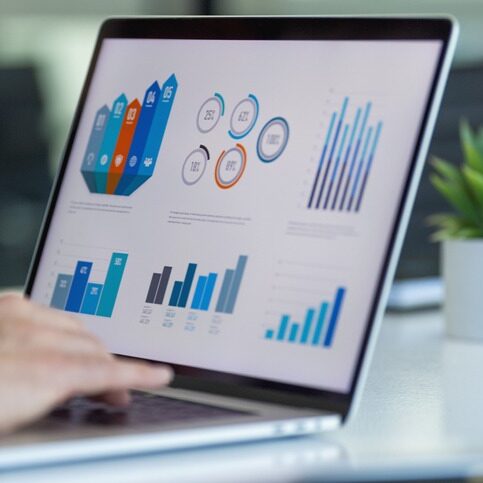 Close up of businessman using a laptop with graphs and charts on a laptop computer. The mans hands can seen typing in a keyboard