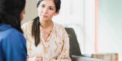 An attentive counselor listens and takes notes as a vulnerable patient discusses an important topic.